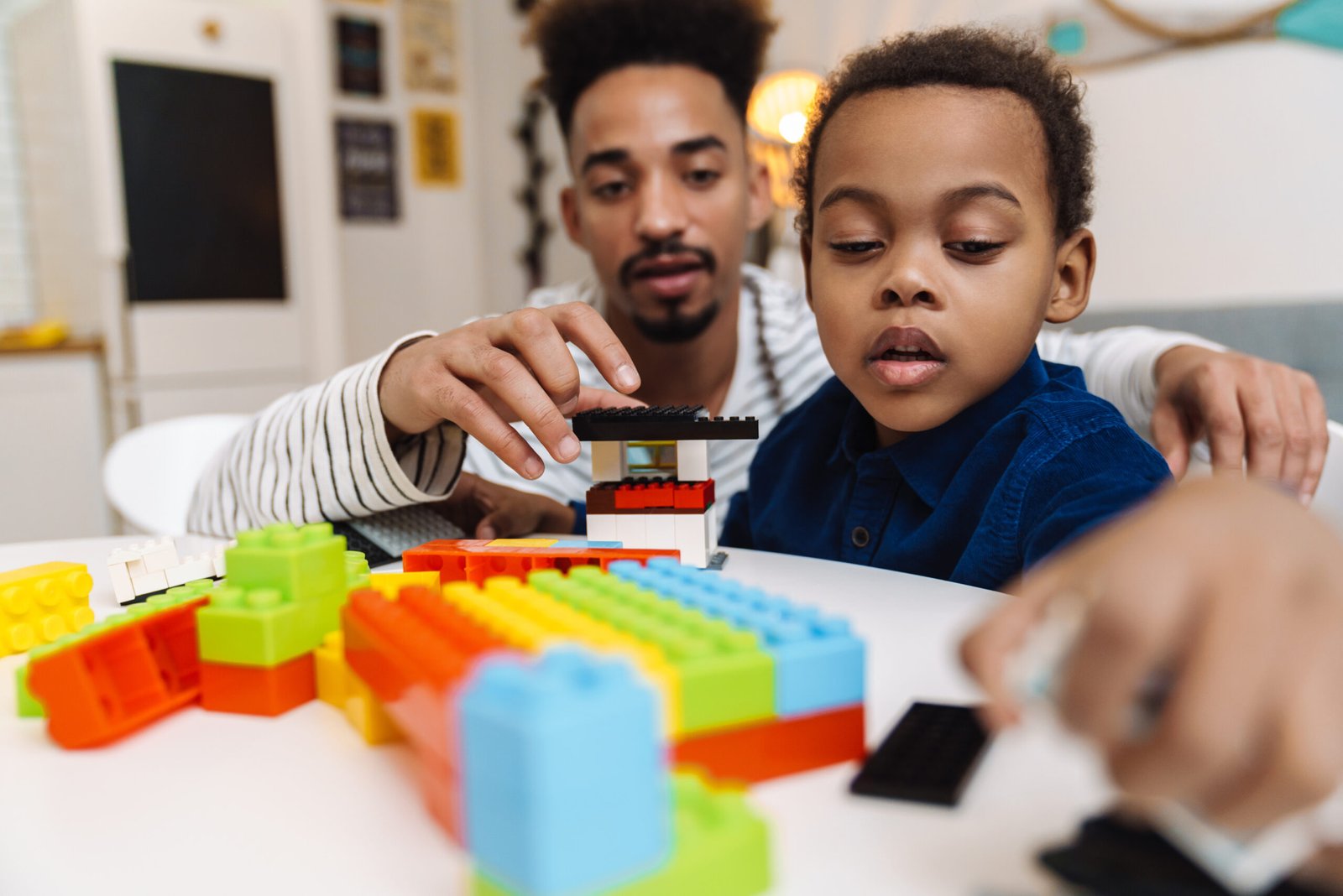 Focused african american boy playing with her young father